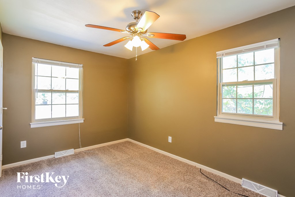 a bedroom with a ceiling fan and two windows