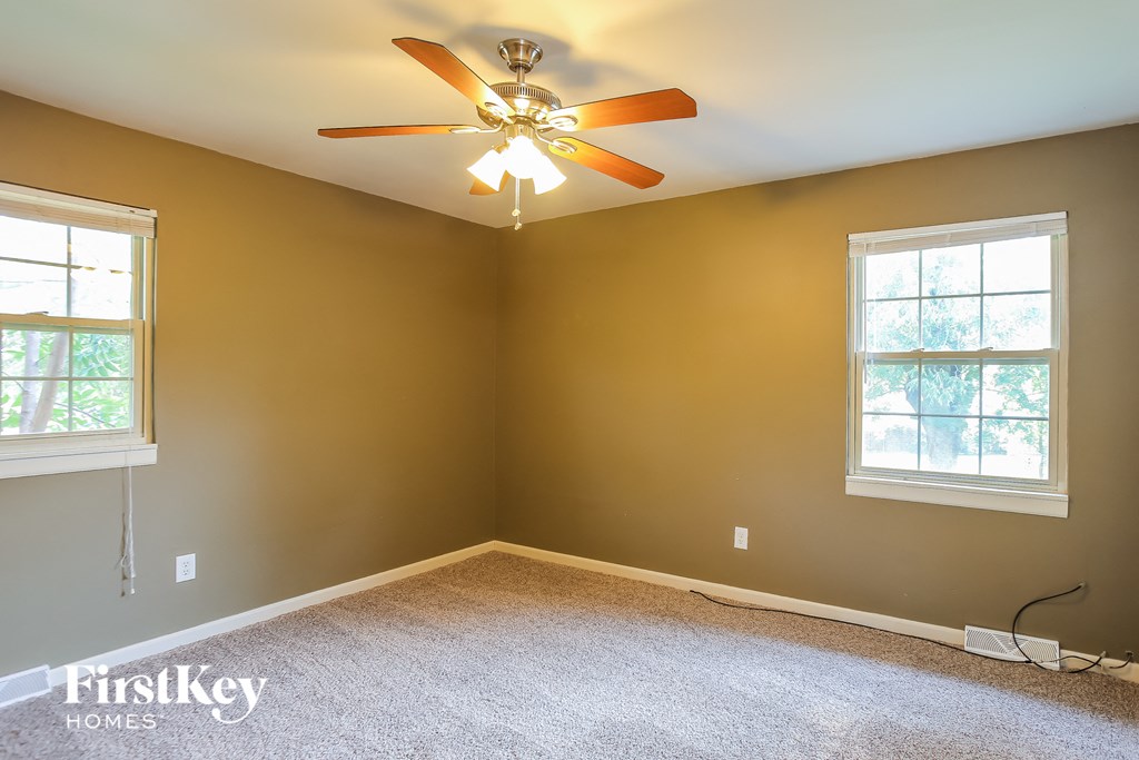 an empty room with a ceiling fan and two windows