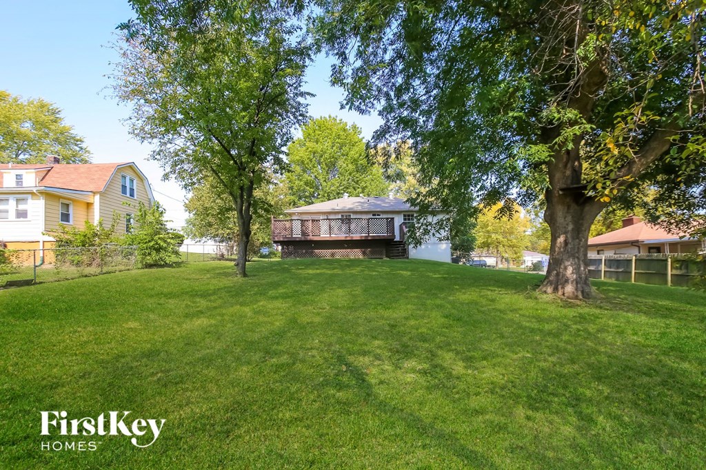 a backyard with a house and a large lawn and trees
