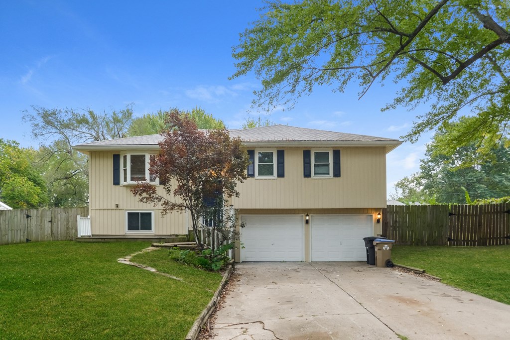 A two-story house with a garage and a tree in front.