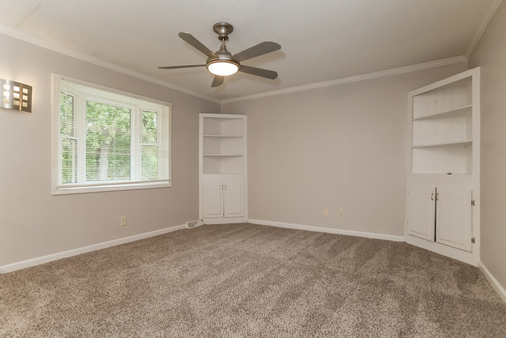 A room with a ceiling fan and a window with blinds.