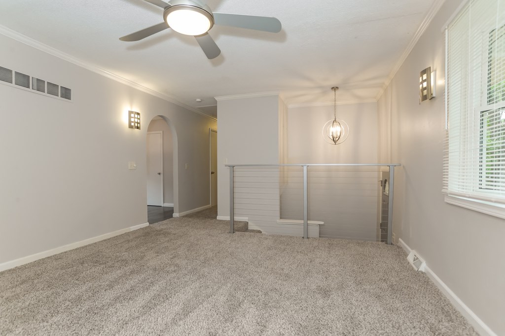 A room with a ceiling fan and carpeted floor.