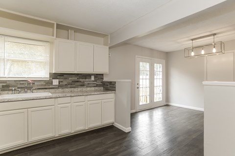 A kitchen with white cabinets and a window.