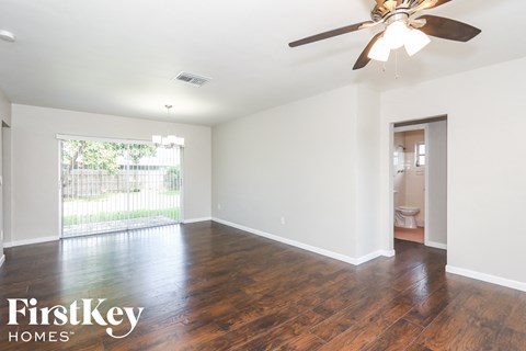 an empty living room with wood floors and a ceiling fan