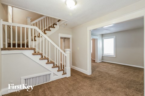 a living room with a staircase and a carpeted floor