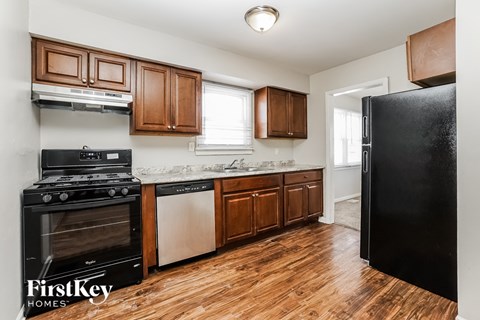 A kitchen with wooden cabinets and a black fridge.