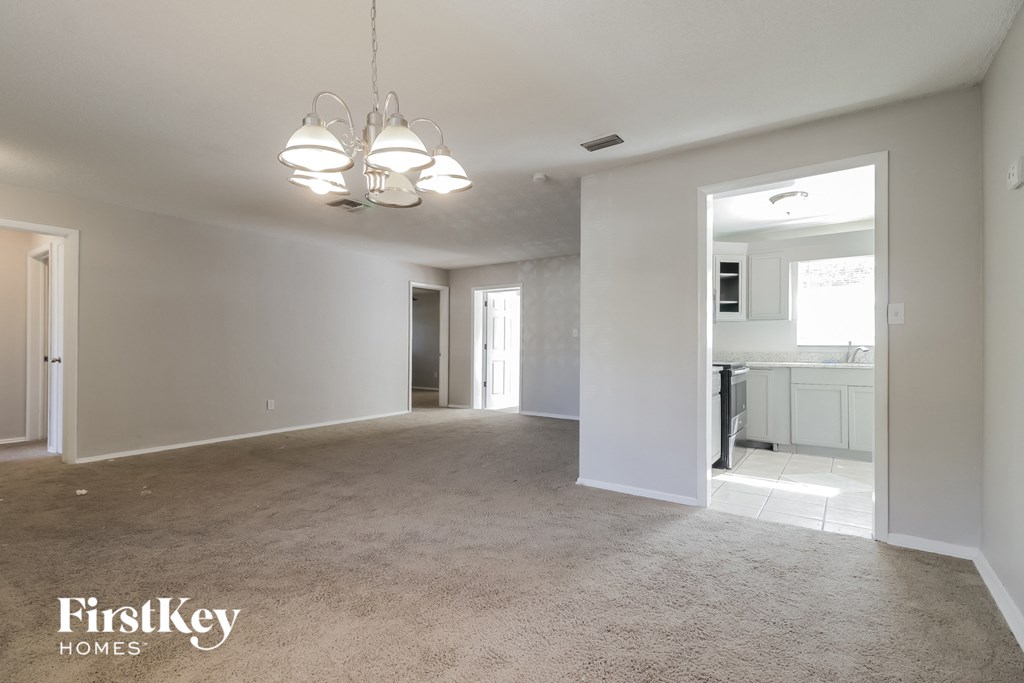an empty living room and kitchen with white walls and carpet