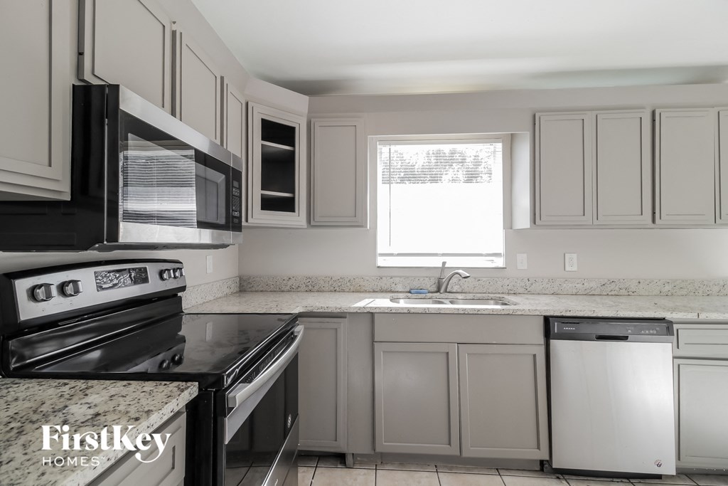 a white kitchen with black appliances and white cabinets