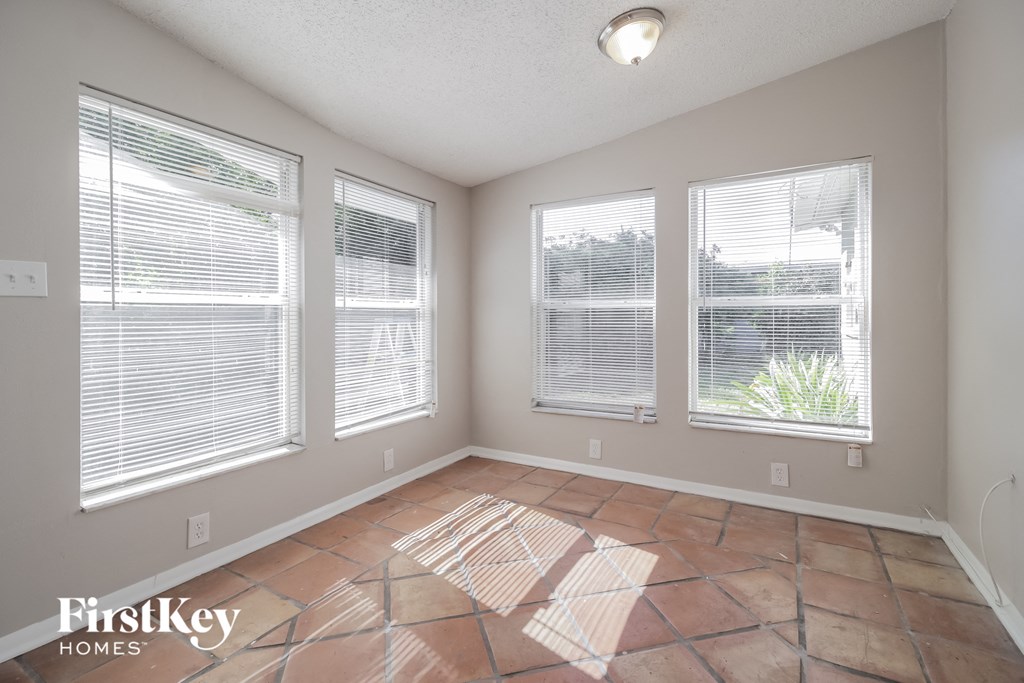 the living room of a home with large windows and tile flooring