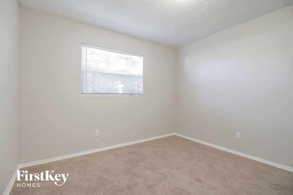 a bedroom with a window and a carpeted floor