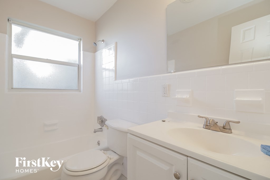 a white bathroom with a sink toilet and mirror