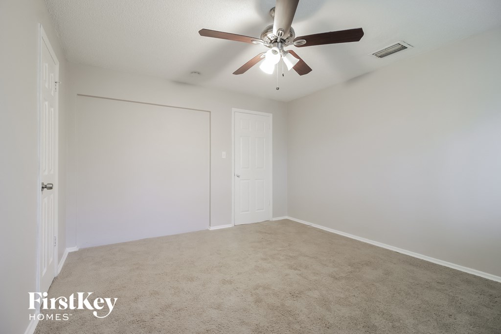 an empty living room with a ceiling fan and white walls