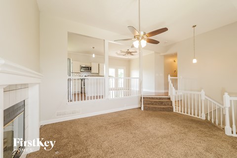 A spacious living room with a fireplace and a staircase.