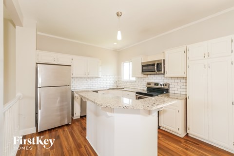 A kitchen with white cabinets and a white island.