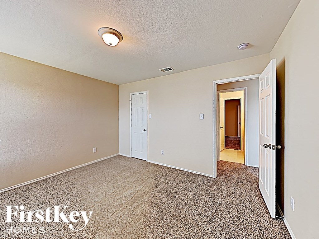 a bedroom with carpeted flooring and a door to a hallway