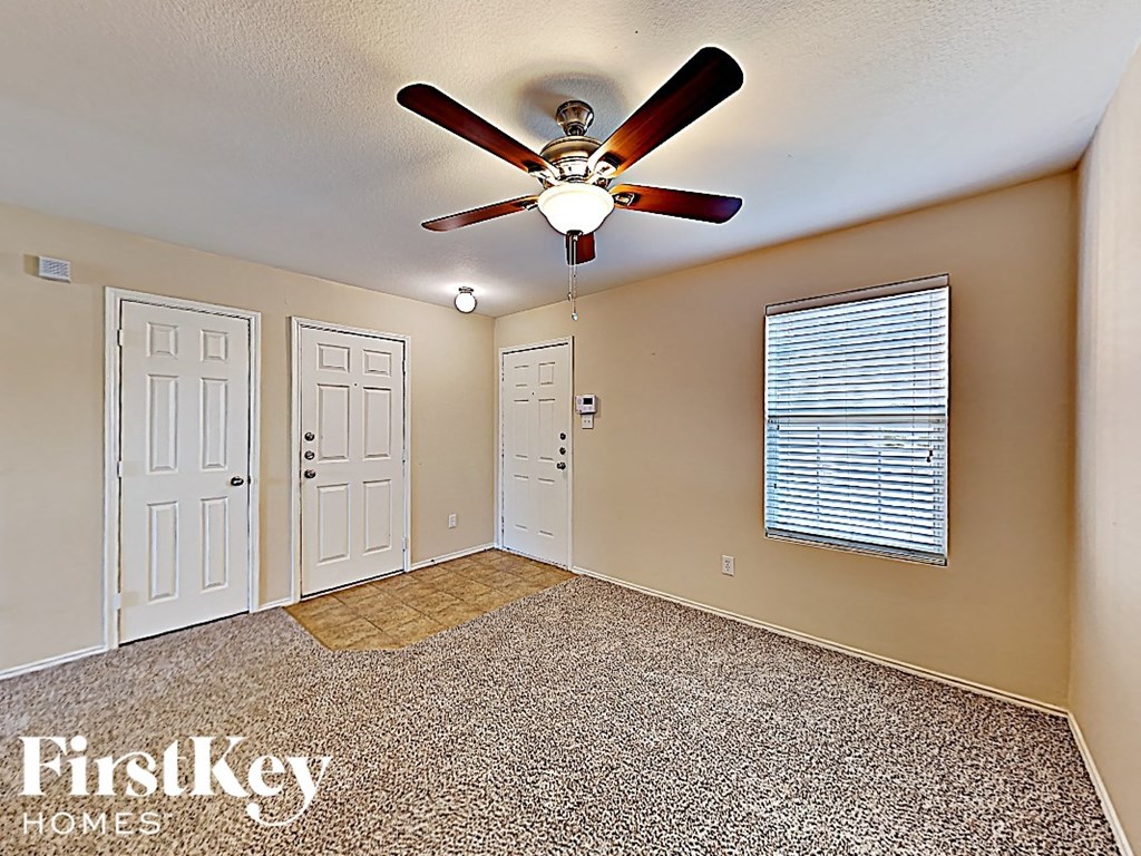 an empty bedroom with a ceiling fan and two doors