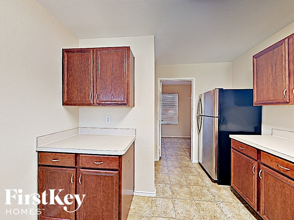 an empty kitchen with wooden cabinets and a refrigerator