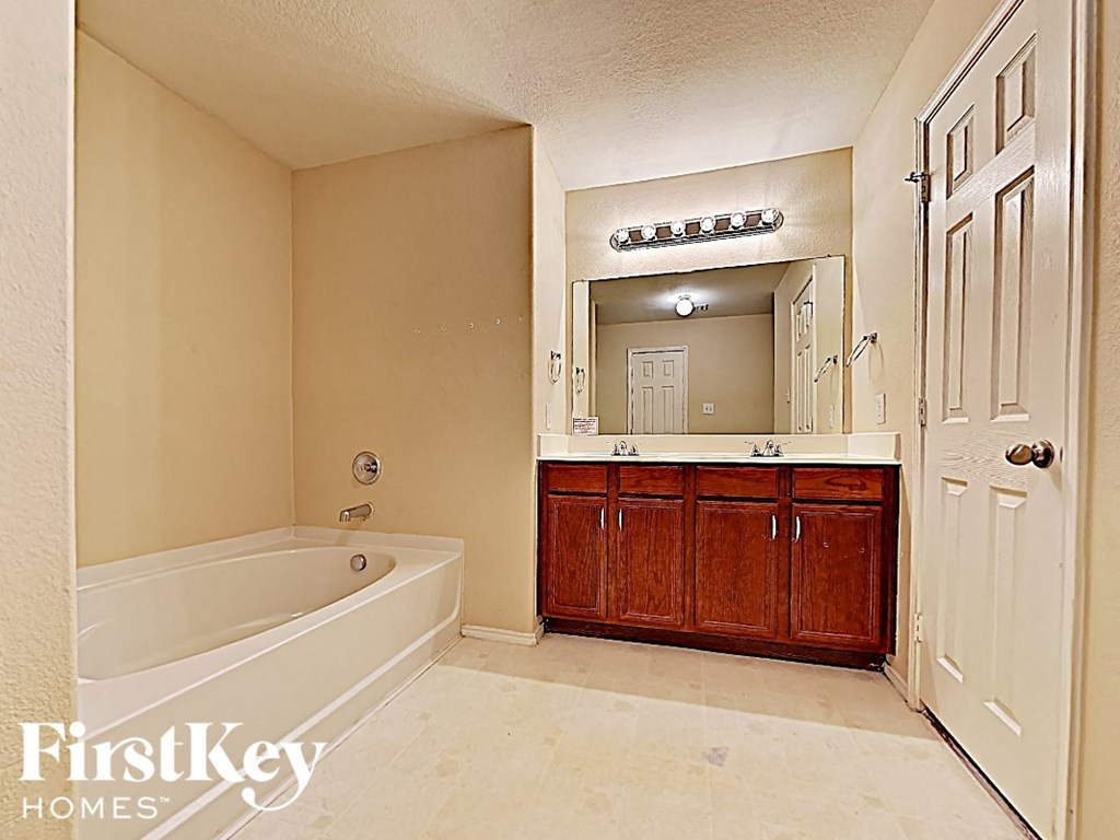 a bathroom with a tub and a sink and a mirror