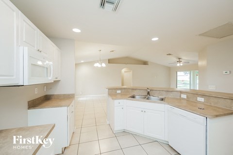 A kitchen with white cabinets and a tiled floor.