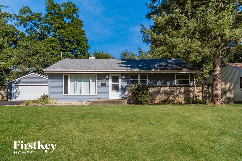 a blue and white house with a yard and trees