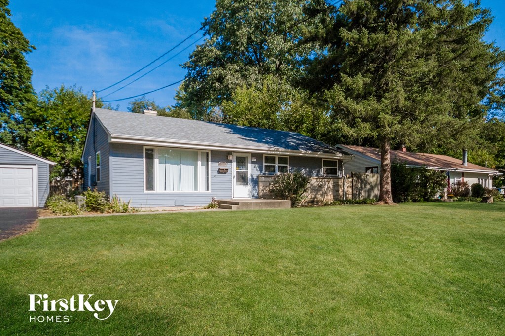 a blue house with a large lawn and a tree