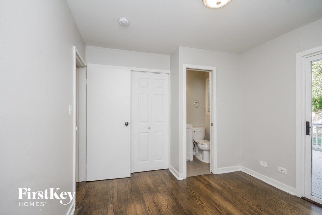 a bedroom with white walls and a door to a bathroom