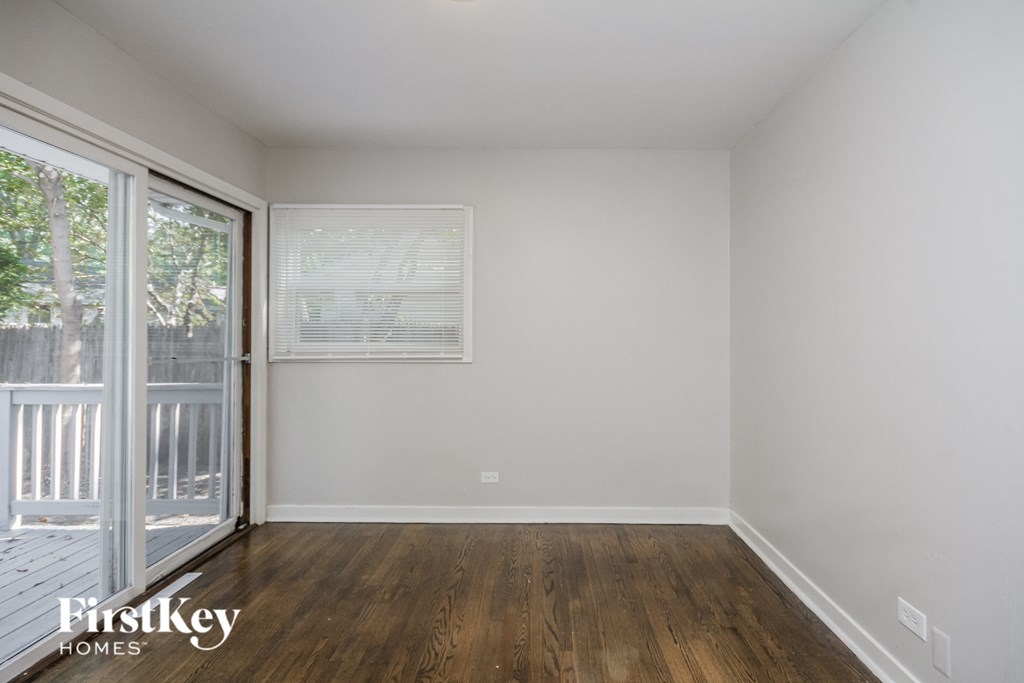a bedroom with white walls and wood floors and a sliding glass door