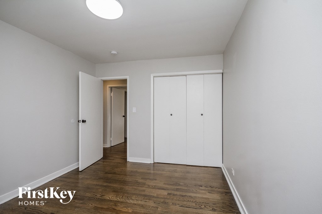 a bedroom with white walls and wood floors and white closets