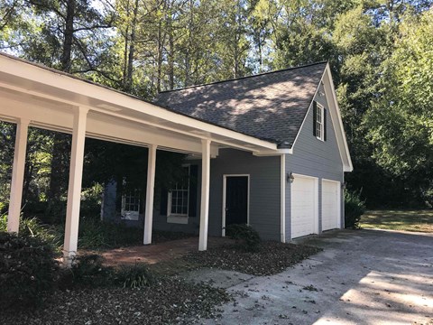 A small house with a grey roof and white garage doors.