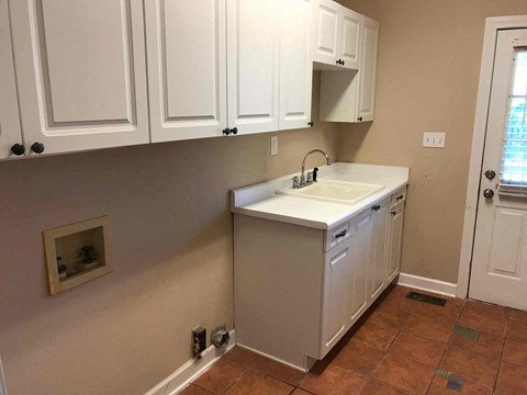 A kitchen with white cabinets and a white sink.
