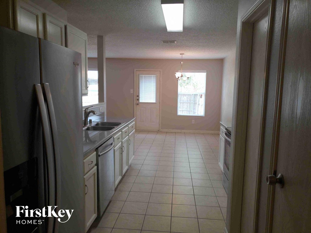 A kitchen with a refrigerator on the left and a door on the right.