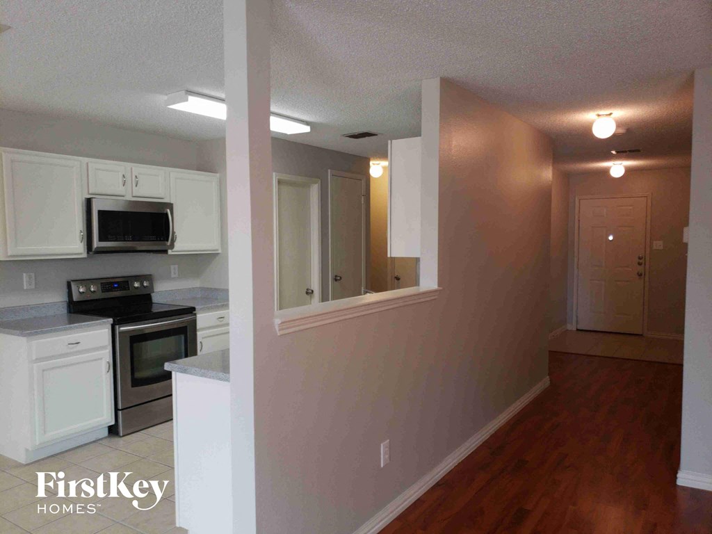 A kitchen with white cabinets and a microwave above the stove.