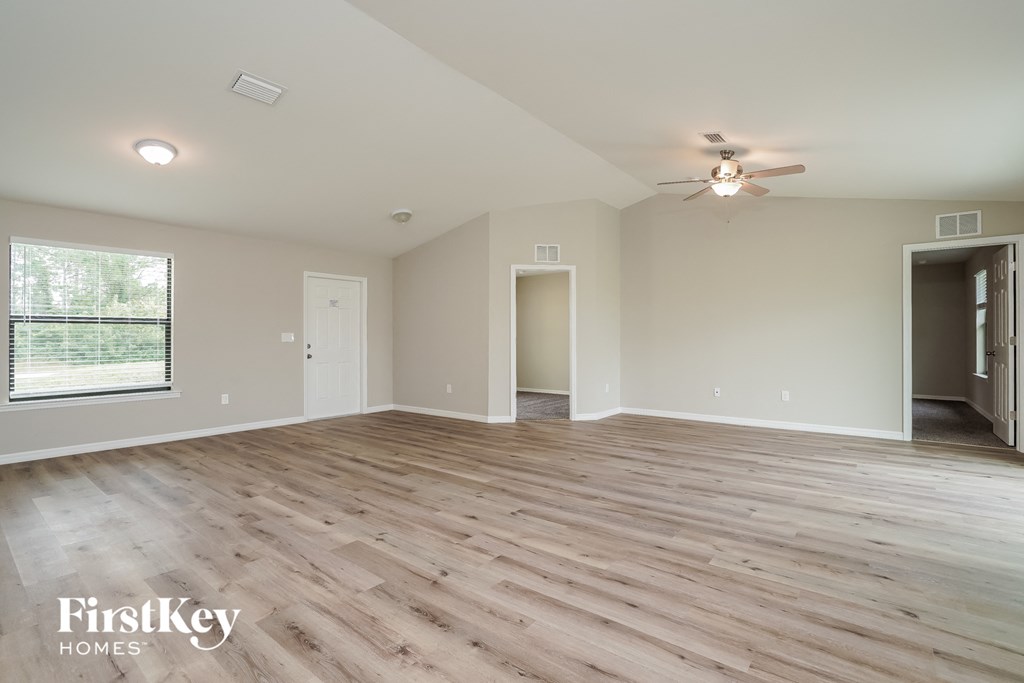A spacious room with wooden flooring and a ceiling fan.