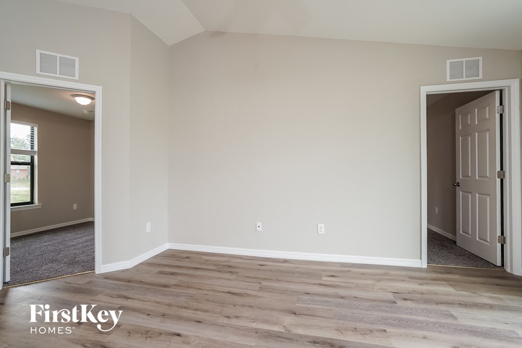 A room with wooden flooring and two doors, one of which is open.
