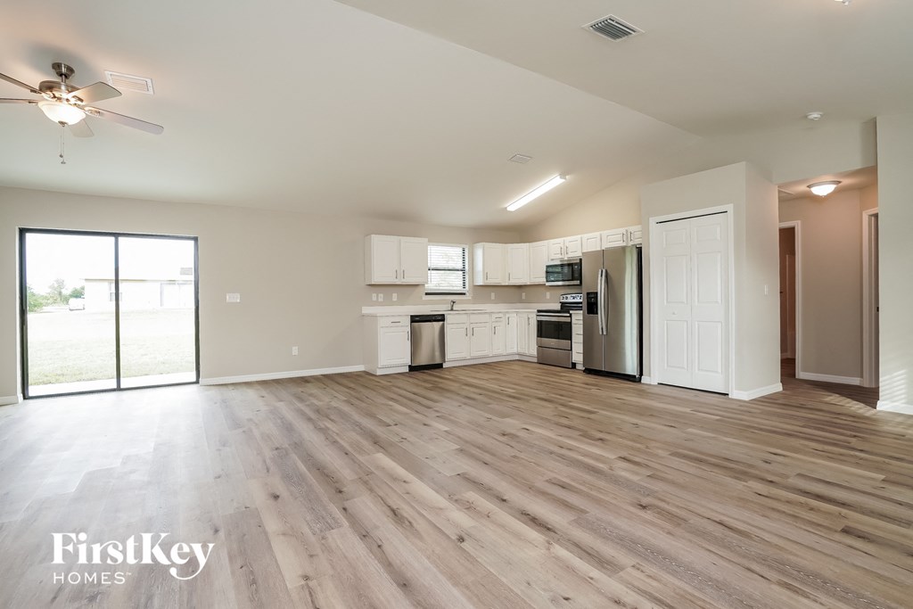 A spacious kitchen with white cabinets and a wooden floor.