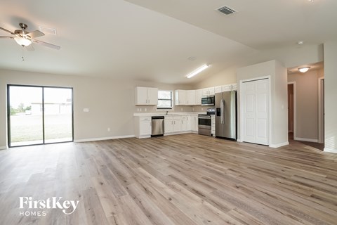 A spacious kitchen with white cabinets and a wooden floor.