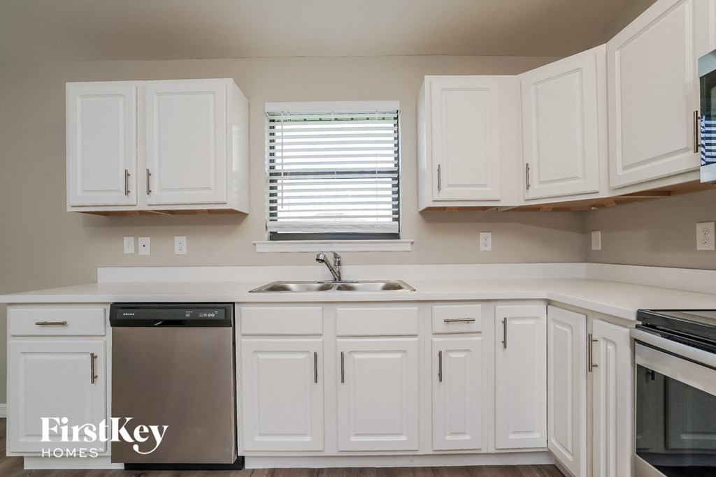 A kitchen with white cabinets and a stainless steel dishwasher.