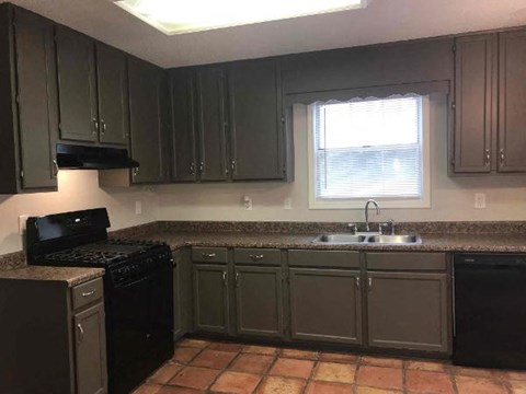 A kitchen with black appliances and brown cabinets.