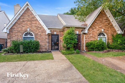 a brick house with a sidewalk and grass in front of it
