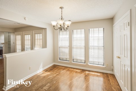 an empty dining room with windows and a chandelier