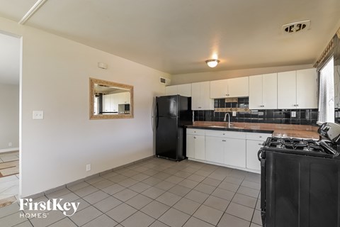A kitchen with a black fridge and white cabinets.