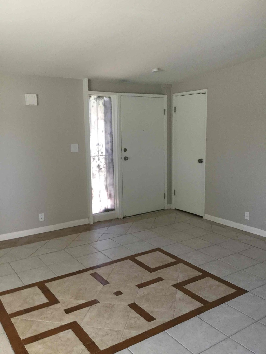 A room with a tiled floor and two doors.