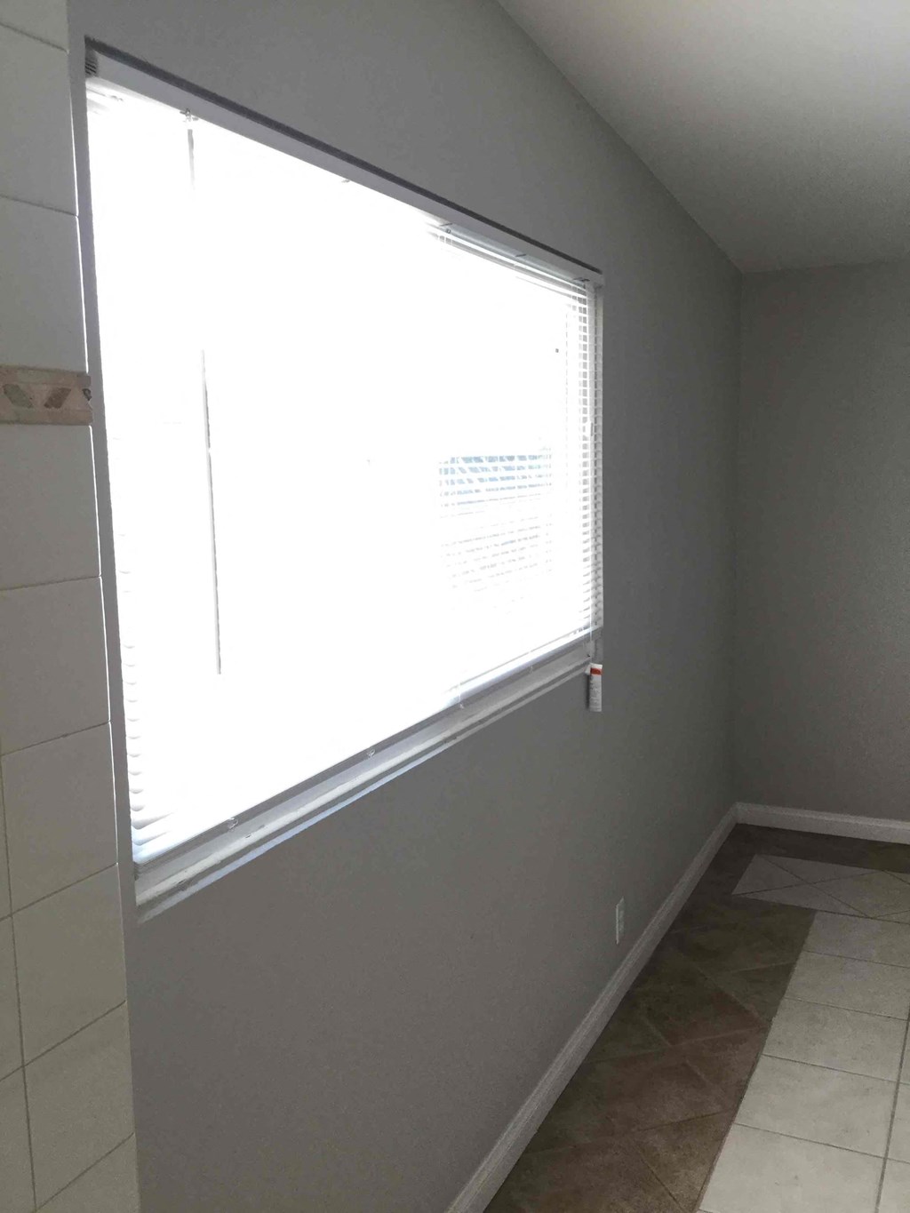 A room with a window and a tiled floor.