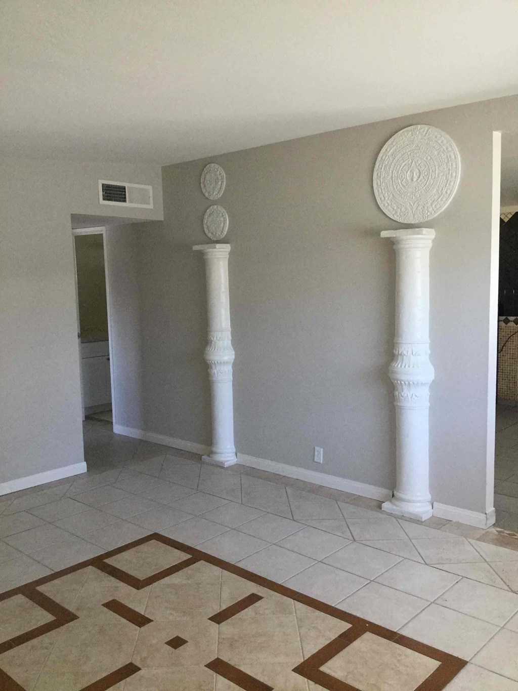 A room with a rug and two white columns.
