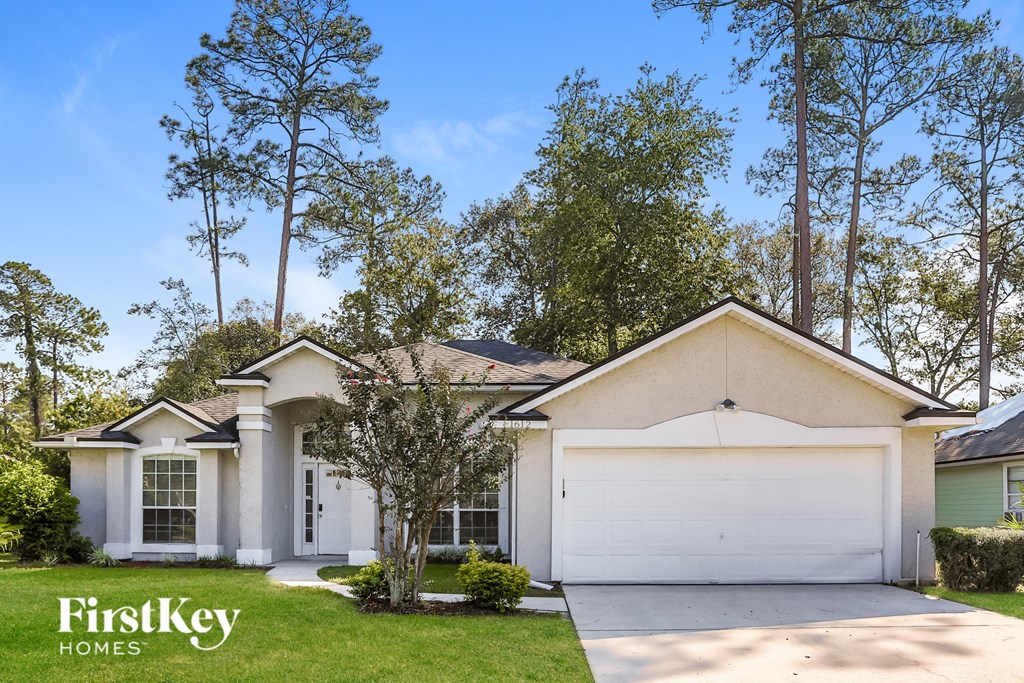 a white house with a white garage door and trees