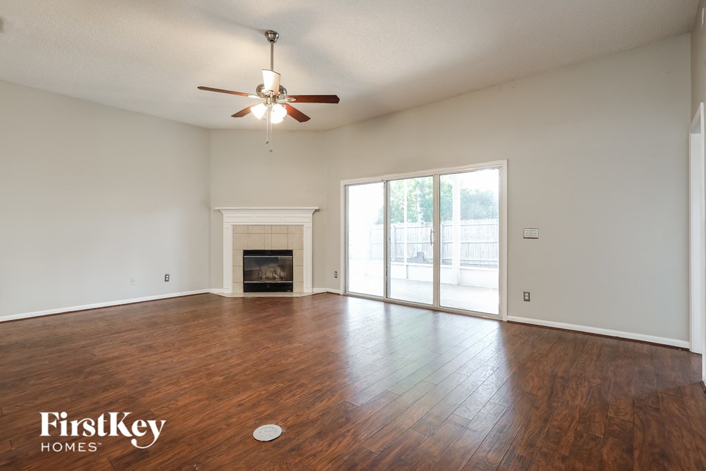 an empty living room with a fireplace and a ceiling fan