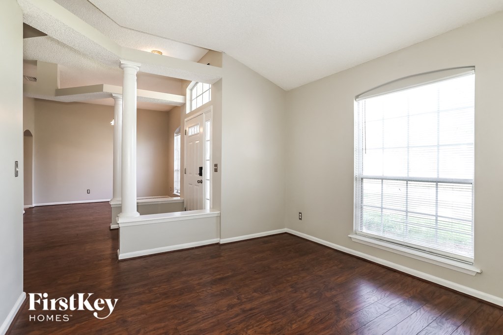 an empty living room with wood flooring and a large window