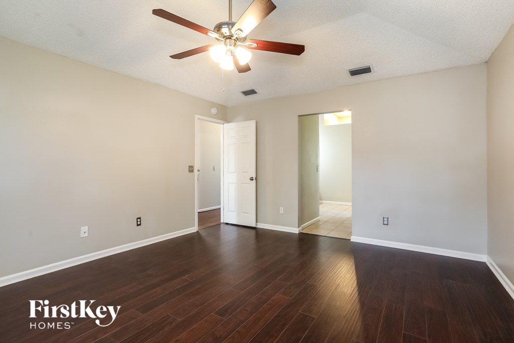 an empty living room with wood floors and a ceiling fan