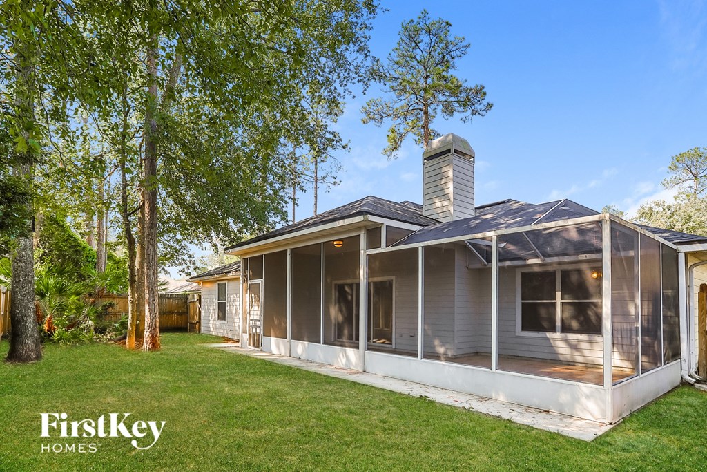 a white and gray house with a porch and a lawn and trees