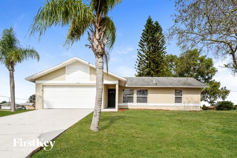 A house with a white garage door and a palm tree in front.